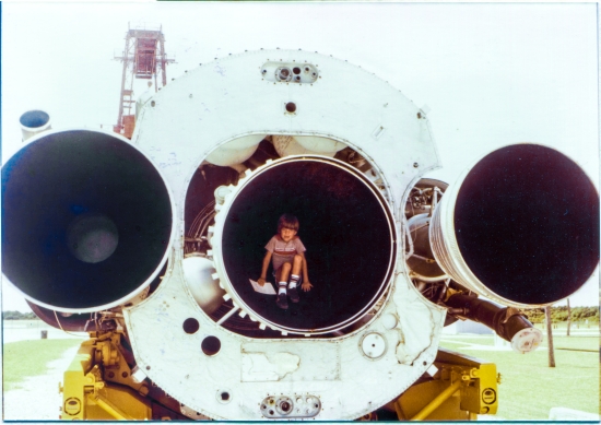 Kai MacLaren is sitting inside the sustainer engine of the Atlas ICBM (flight hardware) on display at the Air Force Space and Missile Museum, Cape Canaveral Air Force Station, Florida. And of course, when you’re very young and very curious, it’s not enough to merely be inside the engine, you must also work yourself as far back into the conical volume as you can, until the narrowing diameter of the nozzle causes you to have to lean over just a bit, as your headroom is reduced more and more, the deeper and deeper you go, into the combustion chamber of the powerplant which propelled this flying machine into the skies. Kai is in his element, and is enjoying it hugely. Photo by James MacLaren.